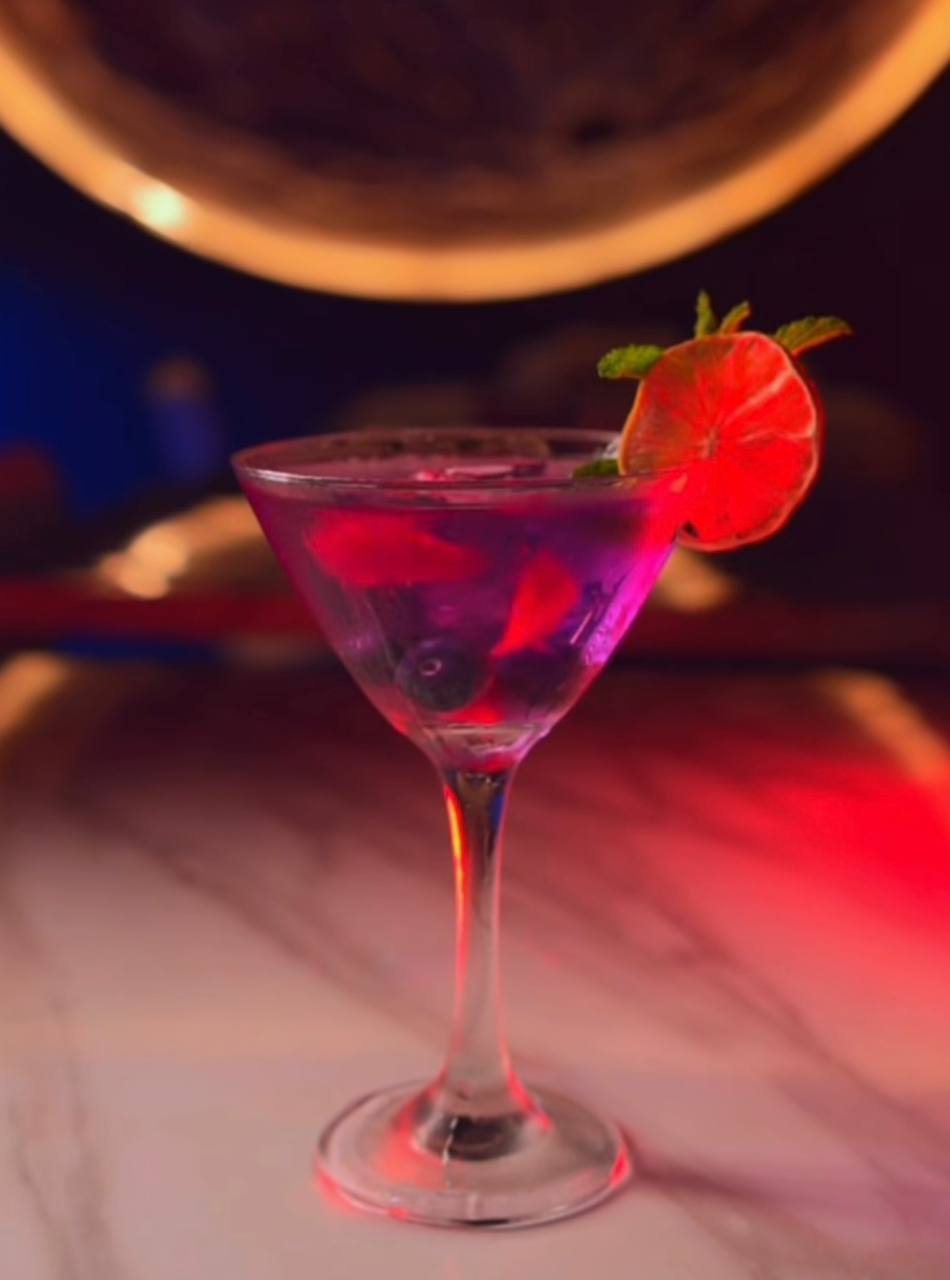 Cóctel violeta con limón y menta frente a la luna iluminada